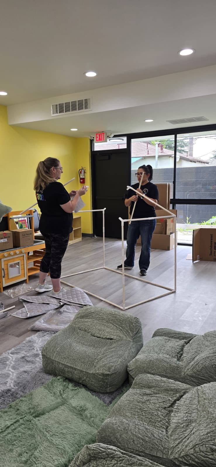 Olivia Martinez-Hauge and Amanda Staples assembling a custom sensory frame during installation.